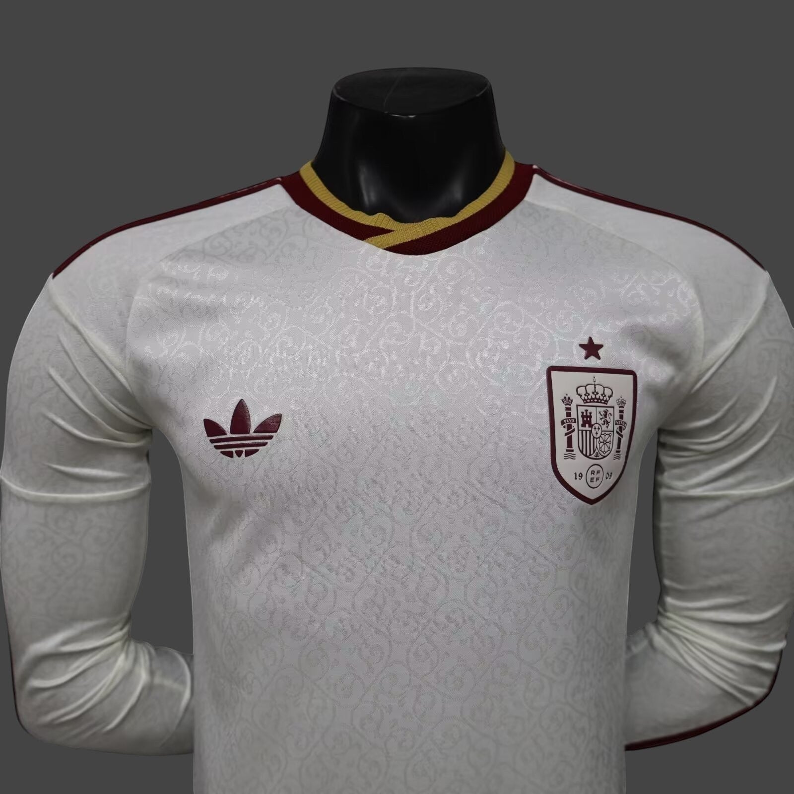 Camiseta de visitante My Store 3 de España, blanca con patrón de espirales, cuello tricolor y logo Adidas Originals.