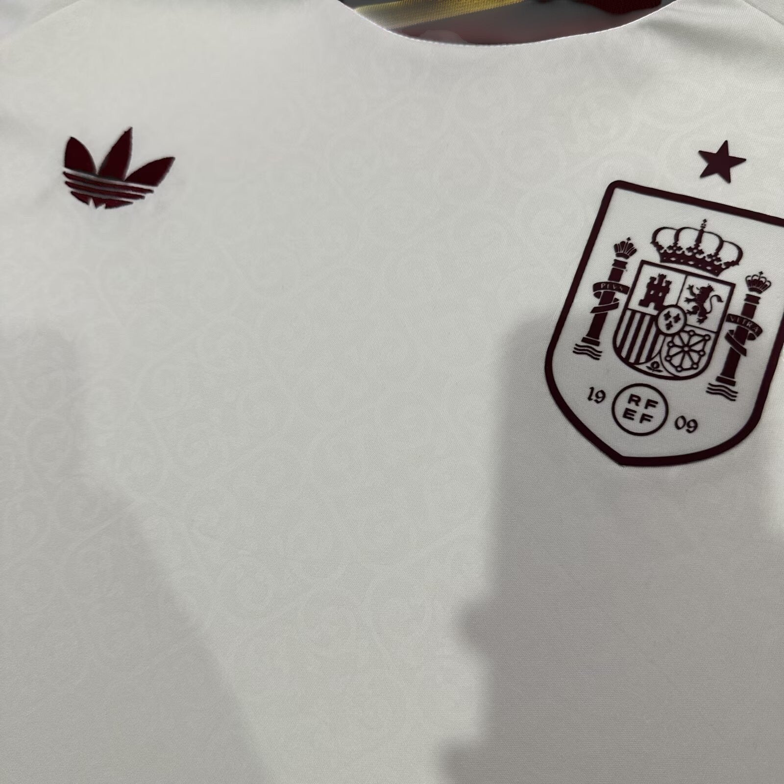 Camiseta visitante My Store 3 de España en blanco con logo Adidas Originals y escudo en granate con patrón de espirales